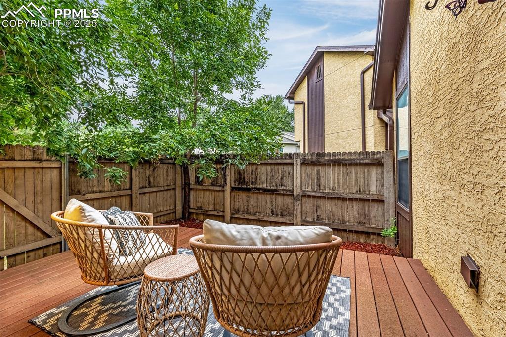 Image 13 of 19: Patio off of primary bedroom, fenced and surrounded by mature trees