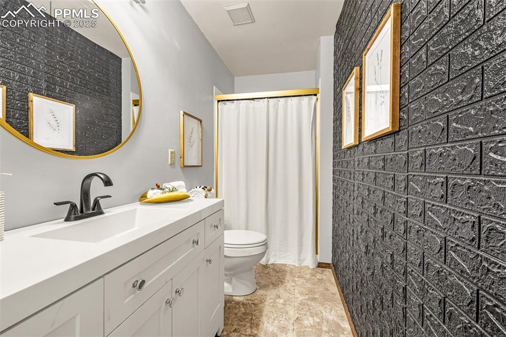 Image 14 of 19: Primary ensuite bath with updated vanity and lighting, spa showerhead