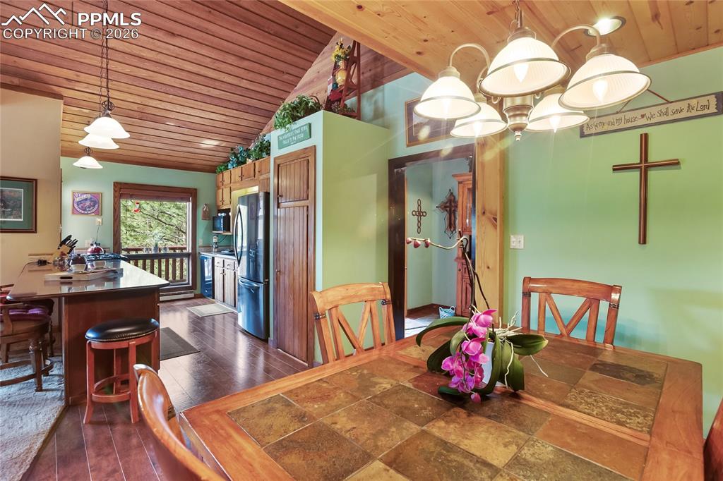 Image 10 of 39: The dining room with wood ceiling, dark wood-style flooring, and lofted cei
