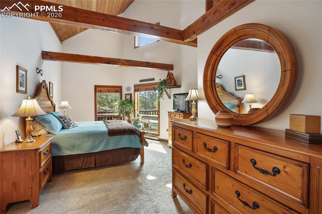 Image 12 of 39: The main bedroom with light colored carpet and wooden vaulted ceiling and e