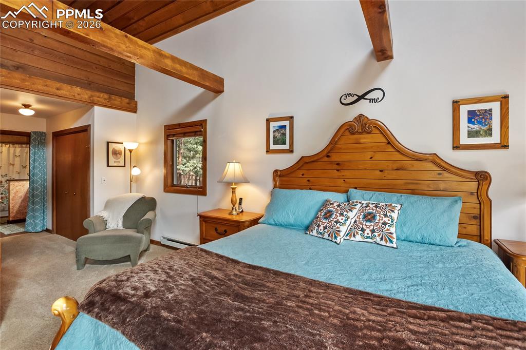 Image 13 of 39: Bedroom with a closet, carpet floors, baseboard heating, exposed beams, and