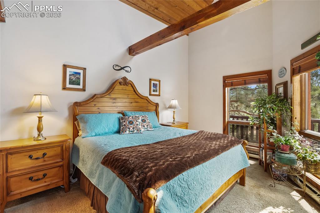 Image 14 of 39: Carpeted bedroom featuring high vaulted ceiling and exposed beamed ceiling