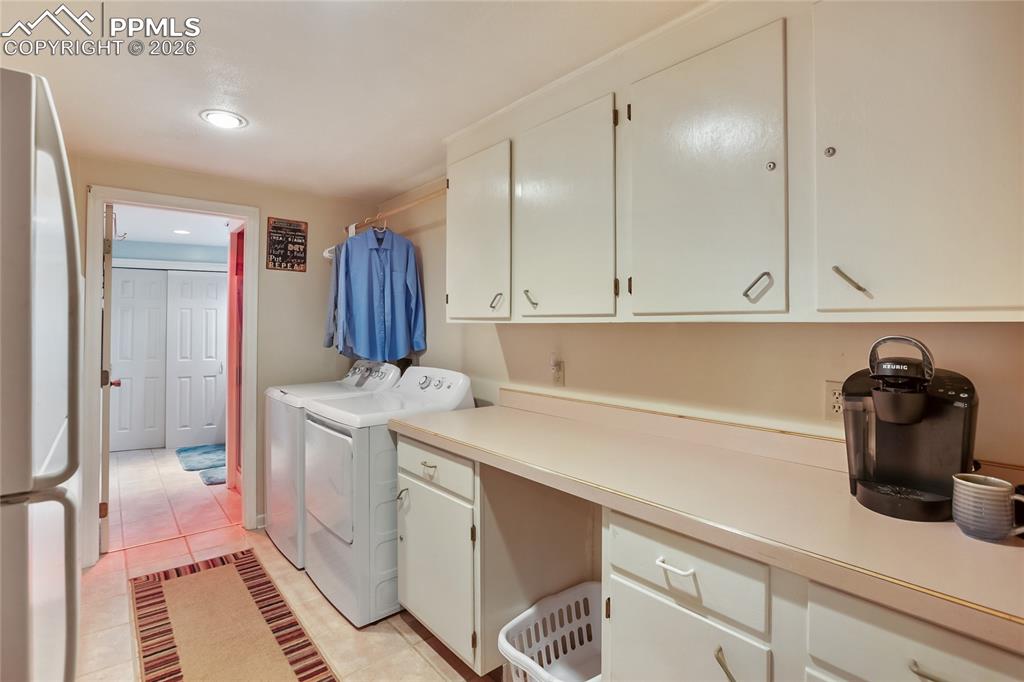 Image 25 of 39: Laundry area with light tile patterned flooring, separate washer and dryer,