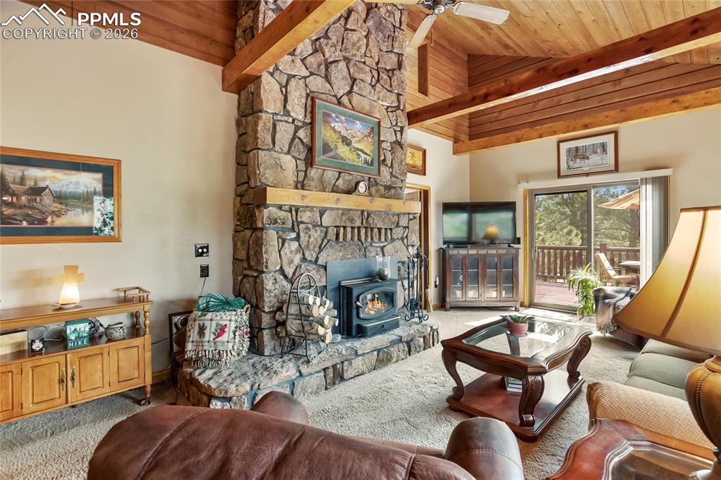 Image 5 of 39: The cozy living room has a high vaulted wood ceiling with exposed beams, a
