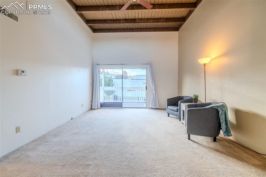 Image 13 of 27: Living area featuring a wood ceiling with exposed beams, a towering ceiling