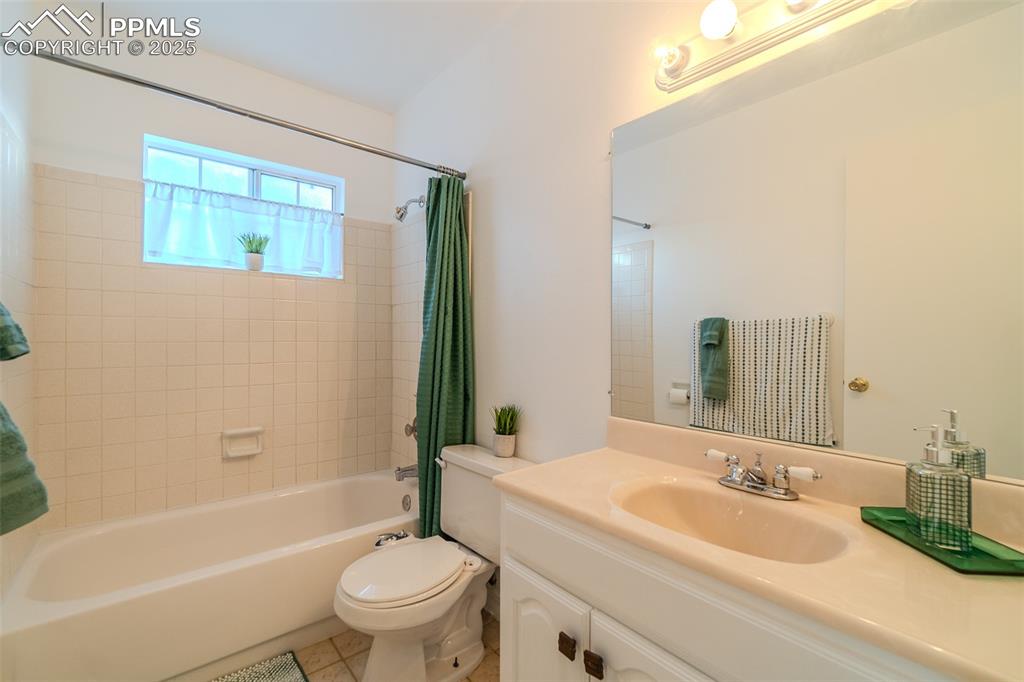 Image 20 of 27: Bathroom with vanity, shower / bath combo with shower curtain, and light ti
