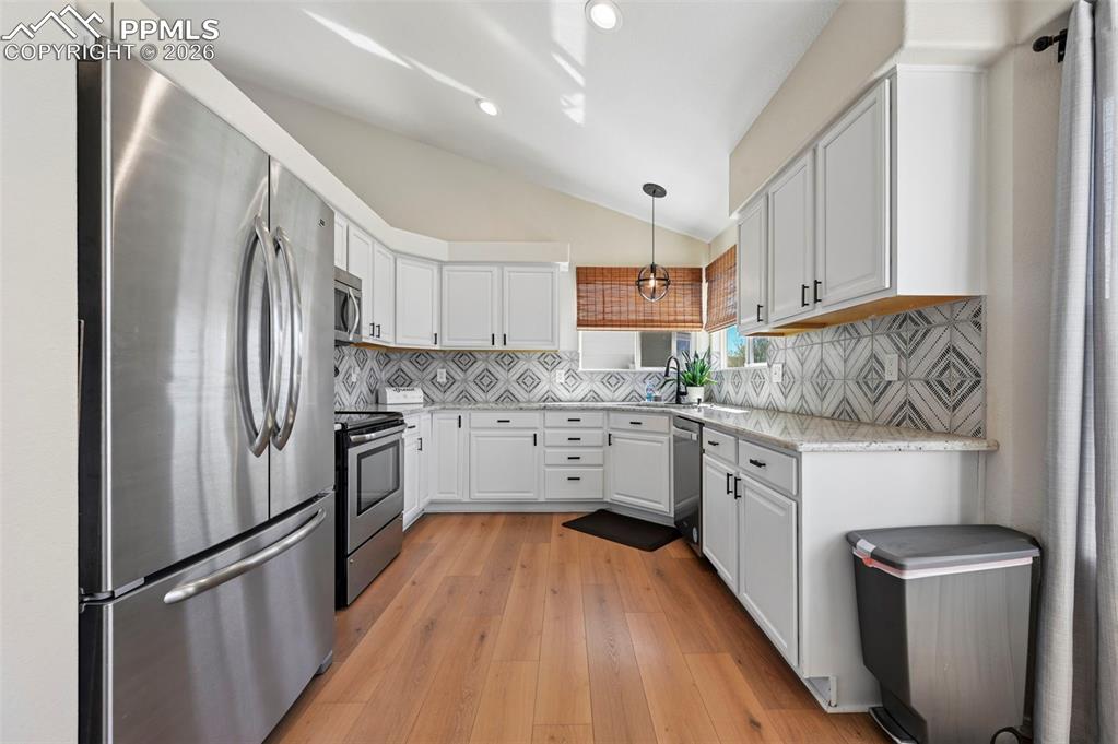 Image 10 of 45: The kitchen features white cabinetry and stainless steel appliances