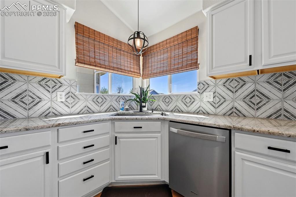 Image 11 of 45: The kitchen features white cabinetry with black hardware, a tiled backsplas