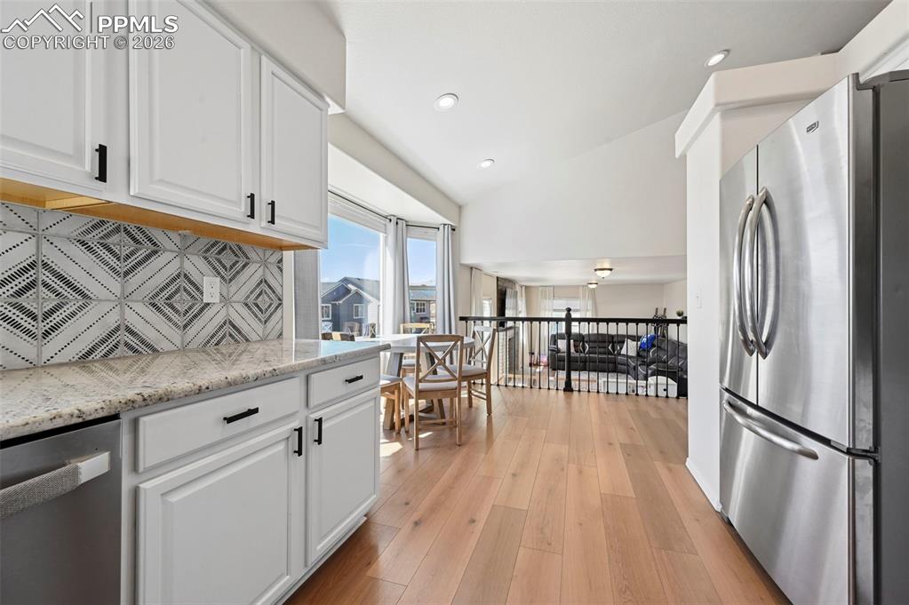 Image 13 of 45: The kitchen features white cabinetry with black hardware, a tiled backsplas