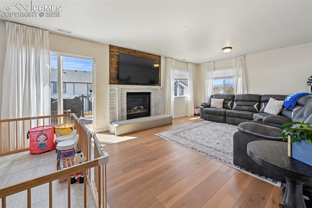 Image 14 of 45: Living area with wood laminate flooring, a fireplace with a light-colored b