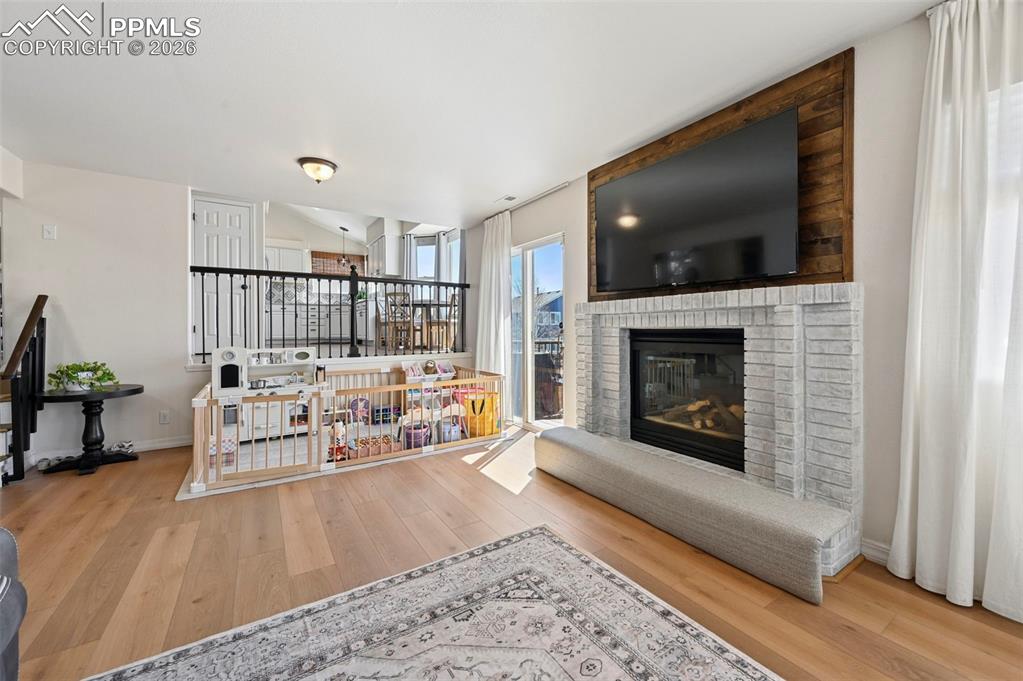 Image 16 of 45: Living area featuring light flooring, a fireplace with a white brick surrou