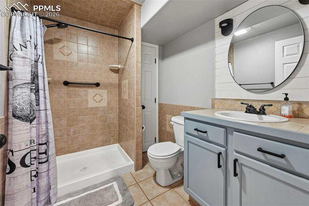 Image 22 of 45: Bathroom featuring a tiled shower with a white base, a toilet, and a vanity