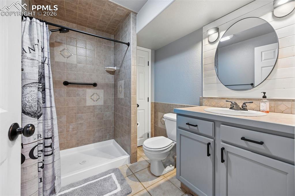 Image 25 of 45: The bathroom features a tiled shower with a white base, a vanity with a whi