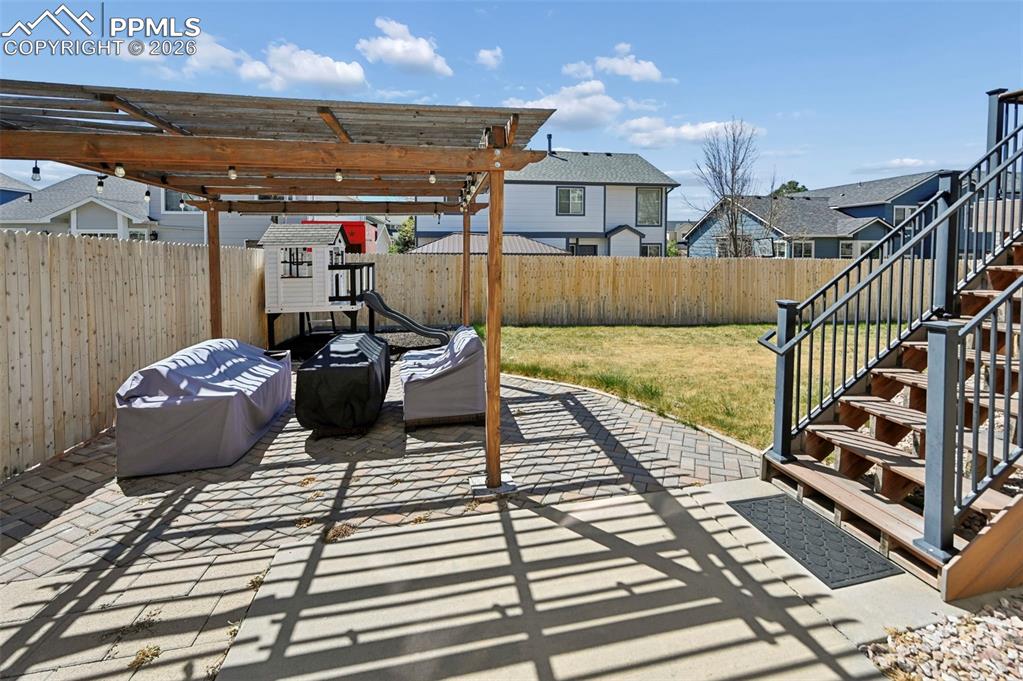 Image 26 of 45: The property features a backyard with a wooden fence, a grass lawn, and a p