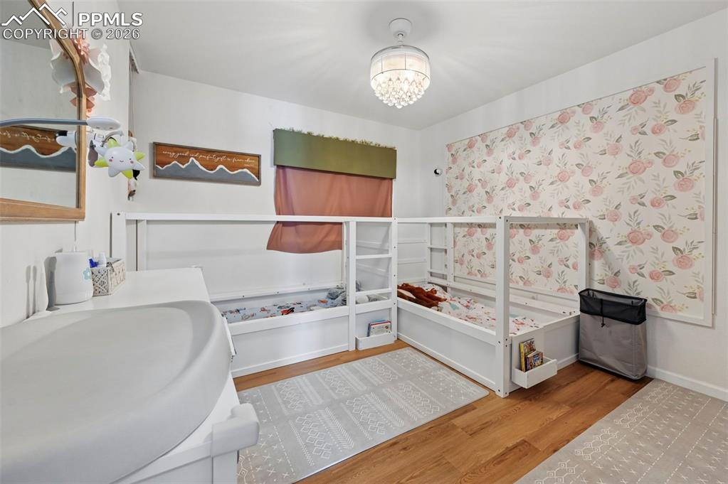 Image 33 of 45: This room features hardwood flooring, white walls, and a decorative wallpap