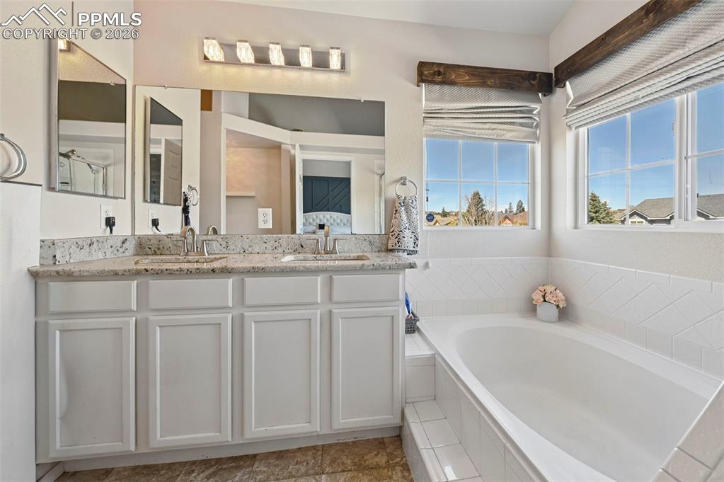 Image 40 of 45: The bathroom features a double vanity with a light-colored granite countert