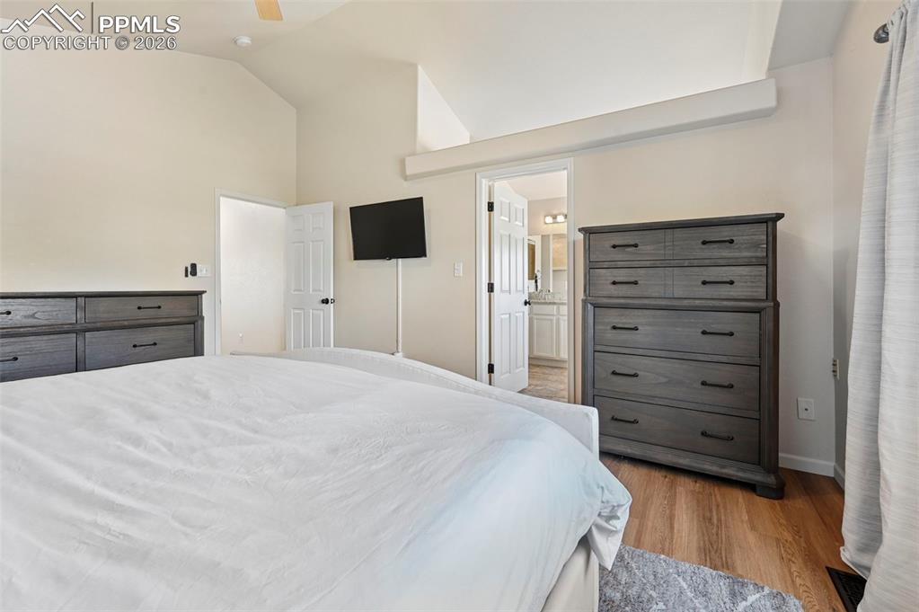 Image 43 of 45: Bedroom featuring a vaulted ceiling, light-colored walls, and wood flooring