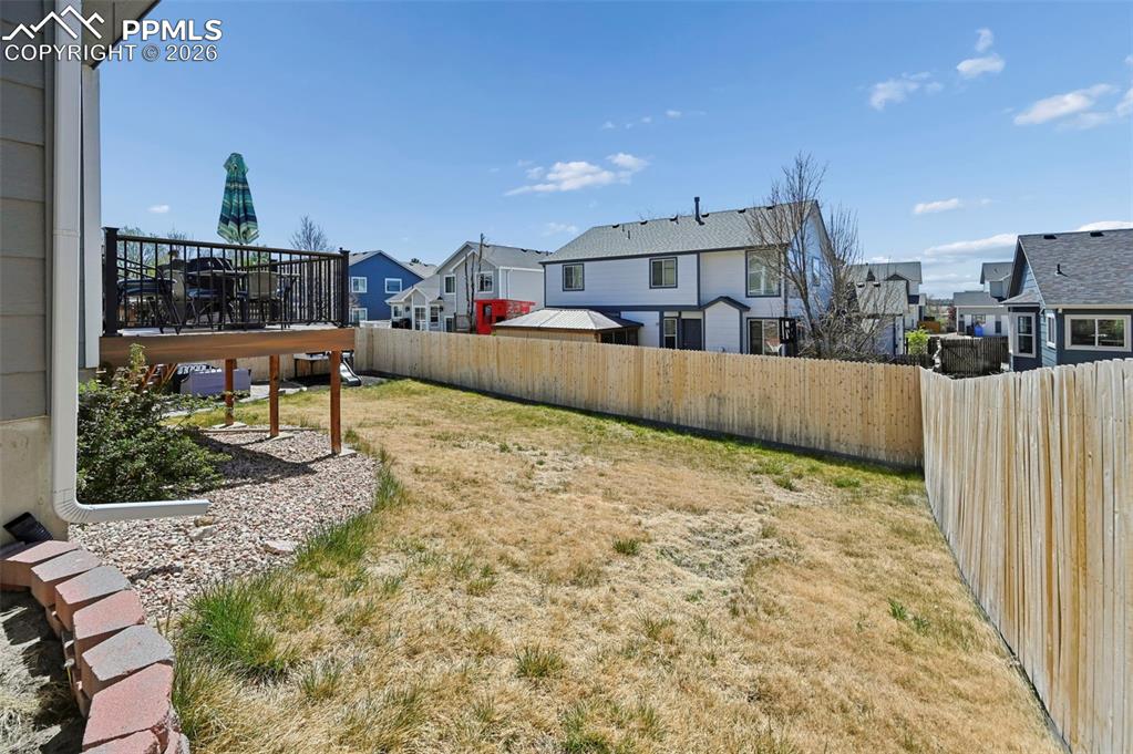 Image 44 of 45: The property features a backyard with a wooden deck, a gravel area, and a l