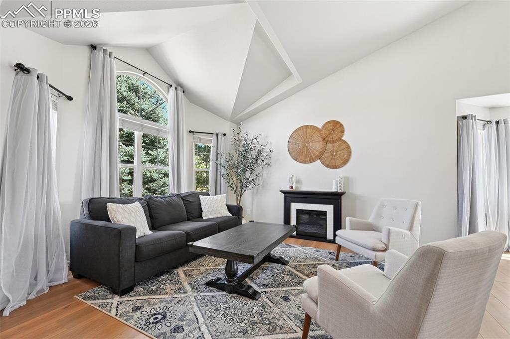 Image 5 of 45: Living area featuring wood laminate floors, high vaulted ceilings, large wi