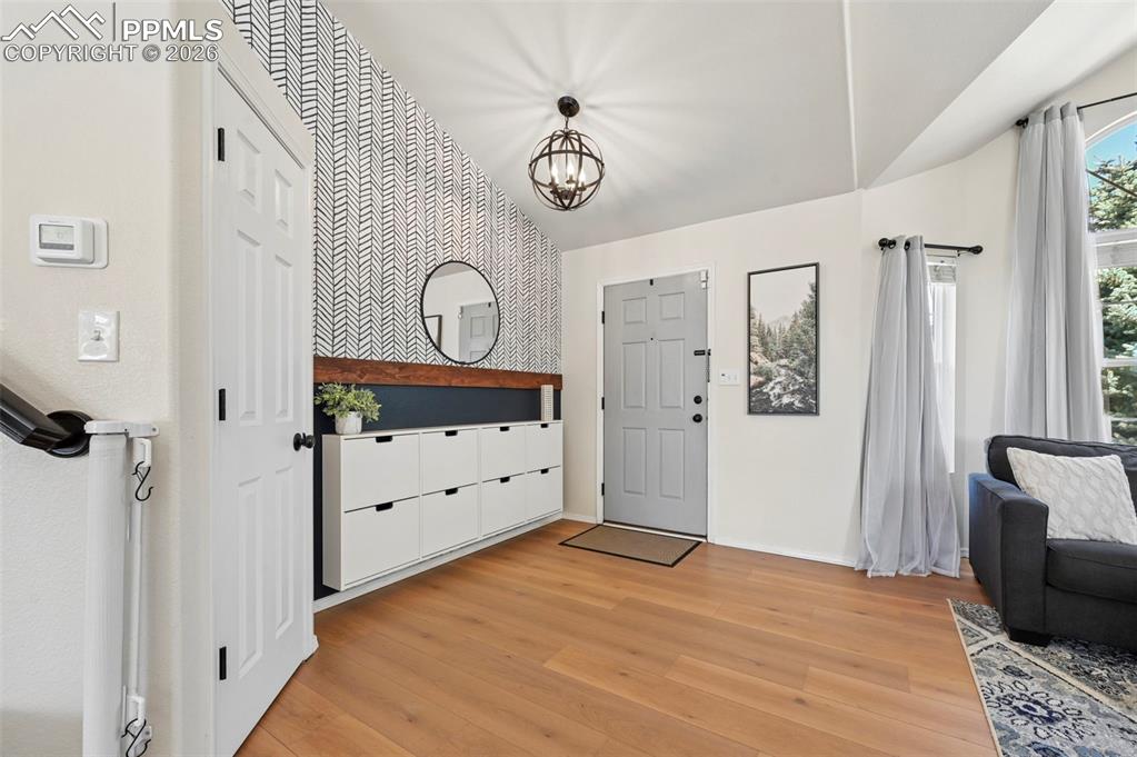Image 6 of 45: Welcoming entryway featuring light wood flooring, a decorative accent wall,