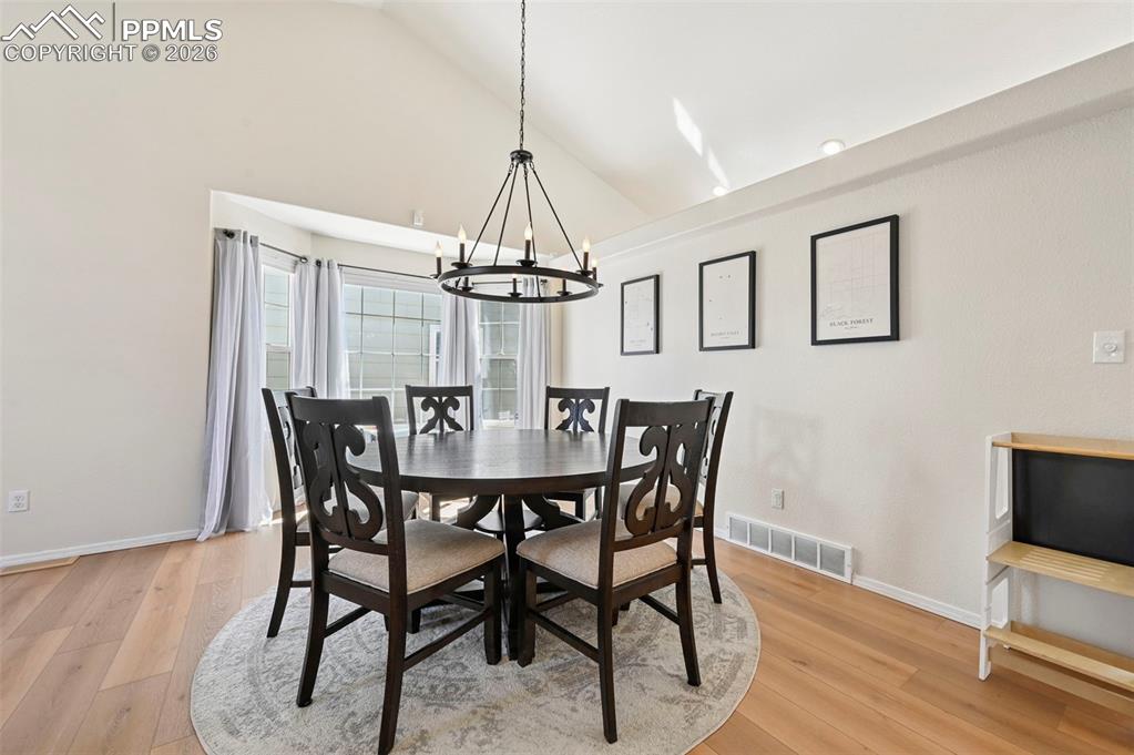 Image 8 of 45: Dining area featuring light laminate wood flooring, a large bay window, and