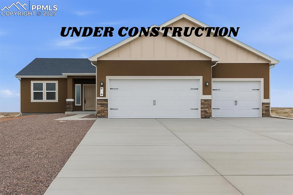 Caption: View of front of home featuring stone siding, driveway, a garage, and stucco siding