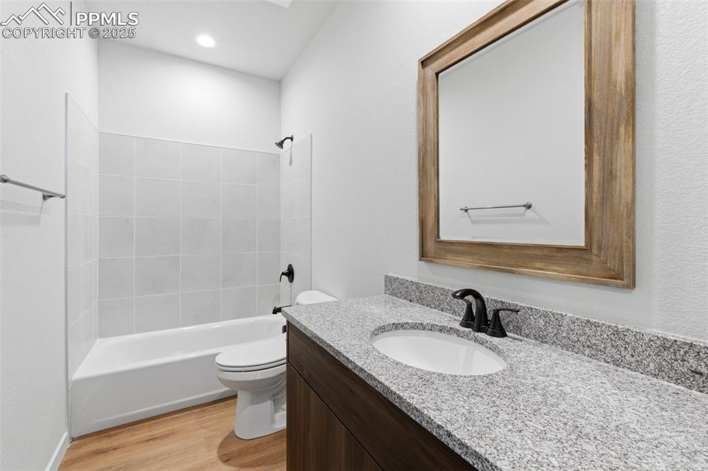 Image 12 of 24: Bathroom with washtub / shower combination, vanity, and light wood-style fl