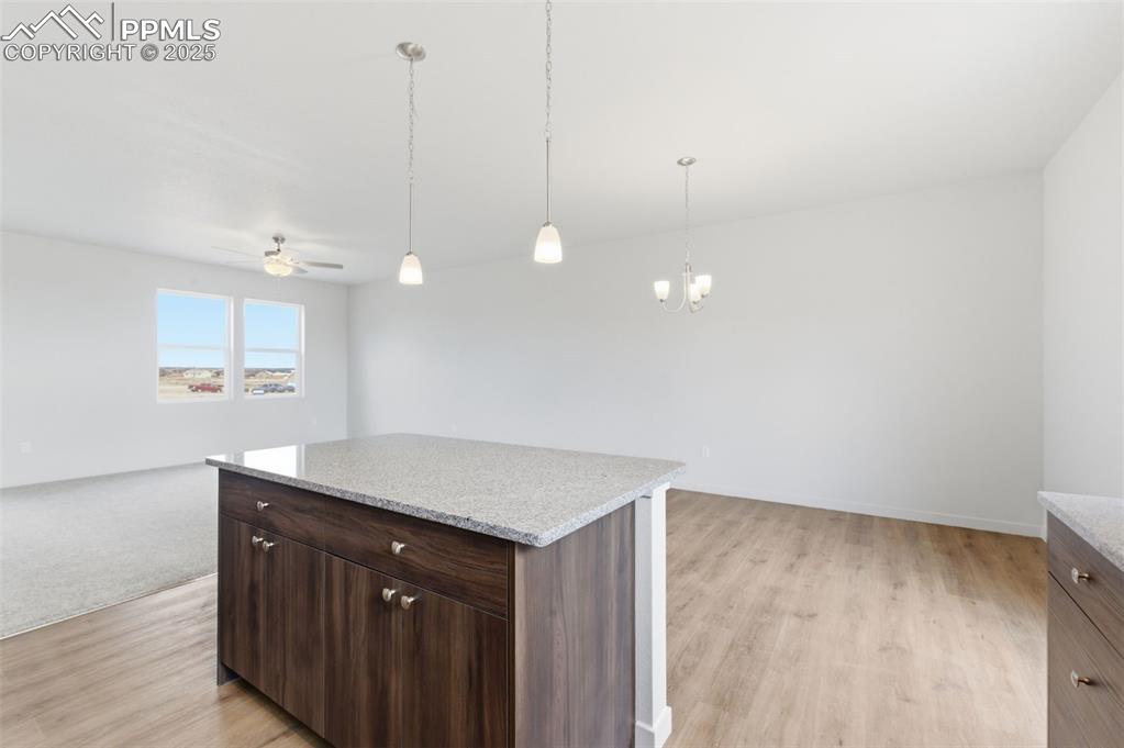 Image 8 of 24: Kitchen featuring open floor plan, dark brown cabinets, decorative light fi