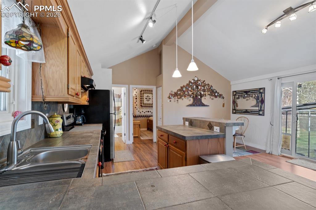 Image 7 of 36: Breakfast bar provides extra workspace!  Penant lights and Tiffany-style tr