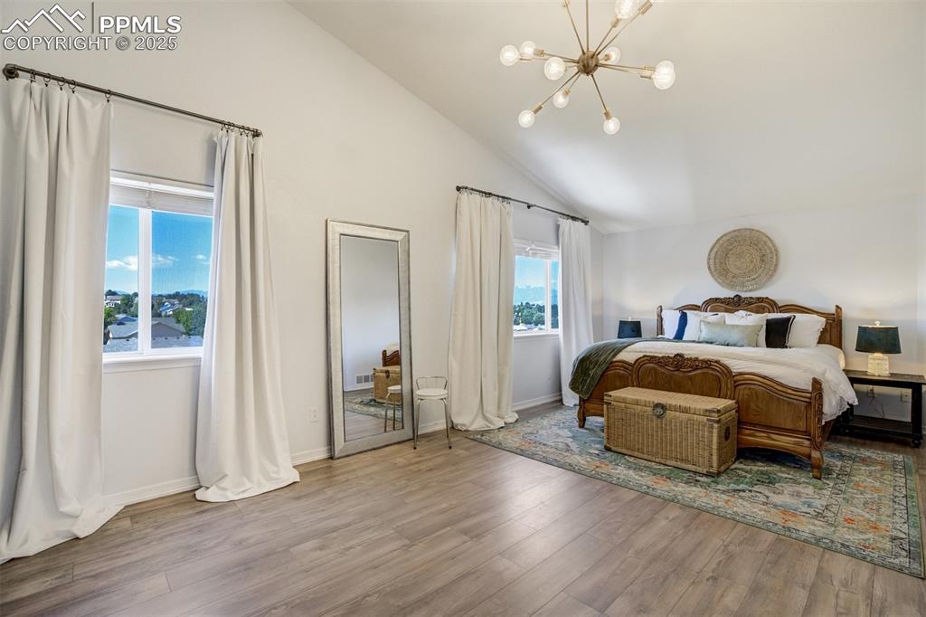 Image 26 of 50: Primary bedroom has new flooring, vaulted ceilings & new lighting. 