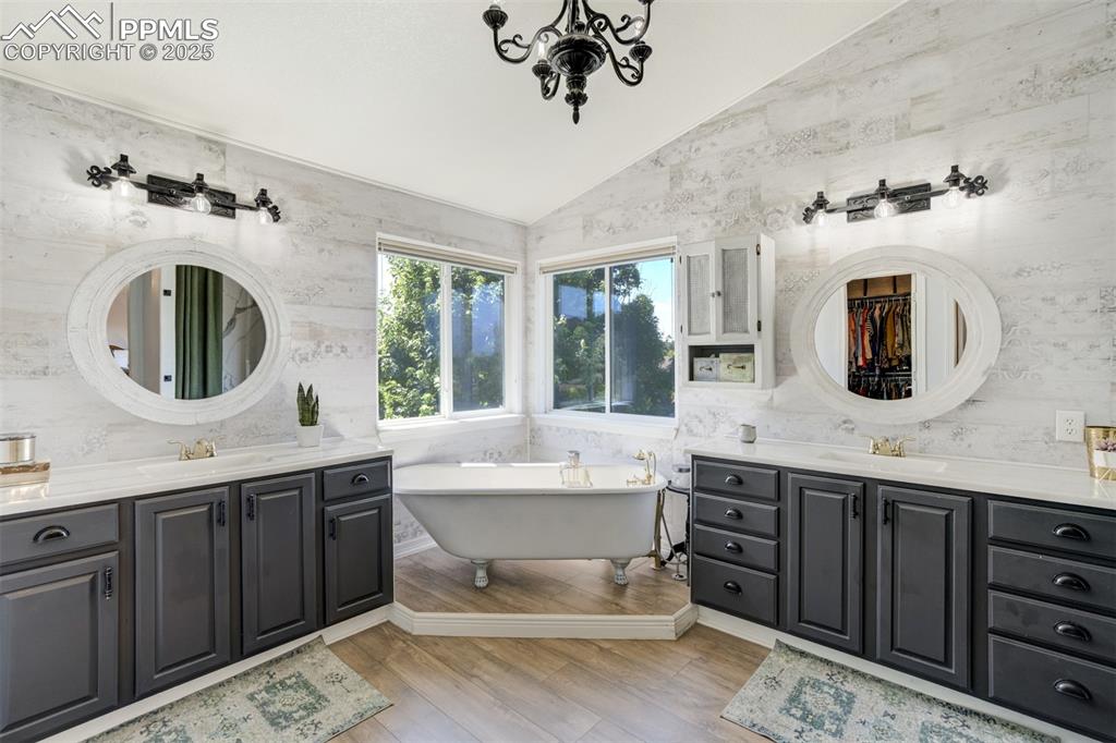 Image 29 of 50: Primary bathroom with separate vanities & claw-foot soaking tub. 