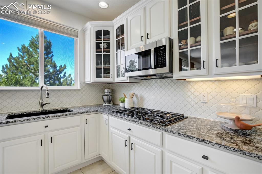 Image 6 of 50: Timeless backsplash, granite counters, gas cooktop, and custom cabinetry. 