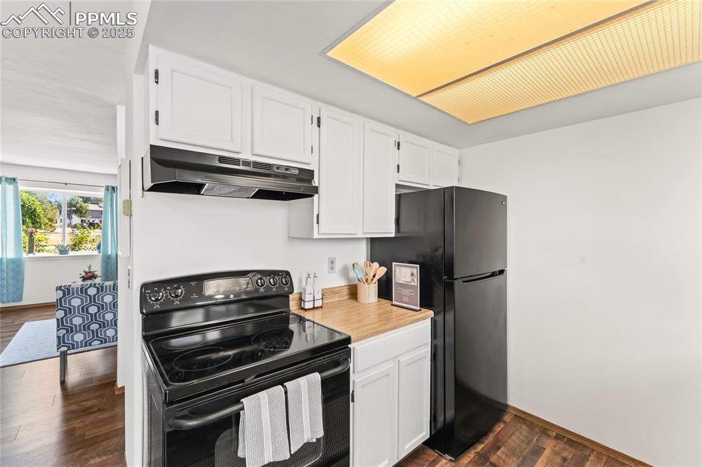 Image 10 of 25: Kitchen featuring black appliances, white cabinets, light countertops, dark