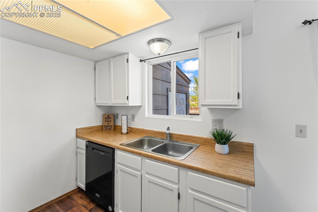 Image 11 of 25: Kitchen with white cabinetry, dishwasher, and light countertops