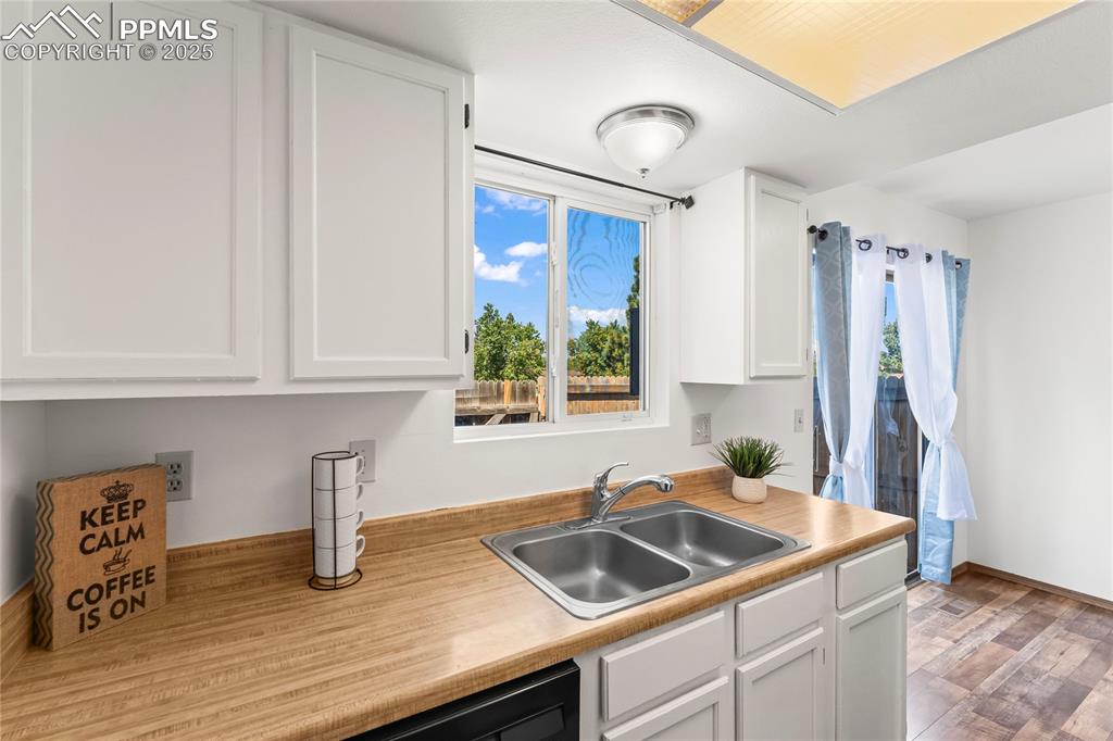 Image 12 of 25: Kitchen with white cabinets and healthy amount of natural light
