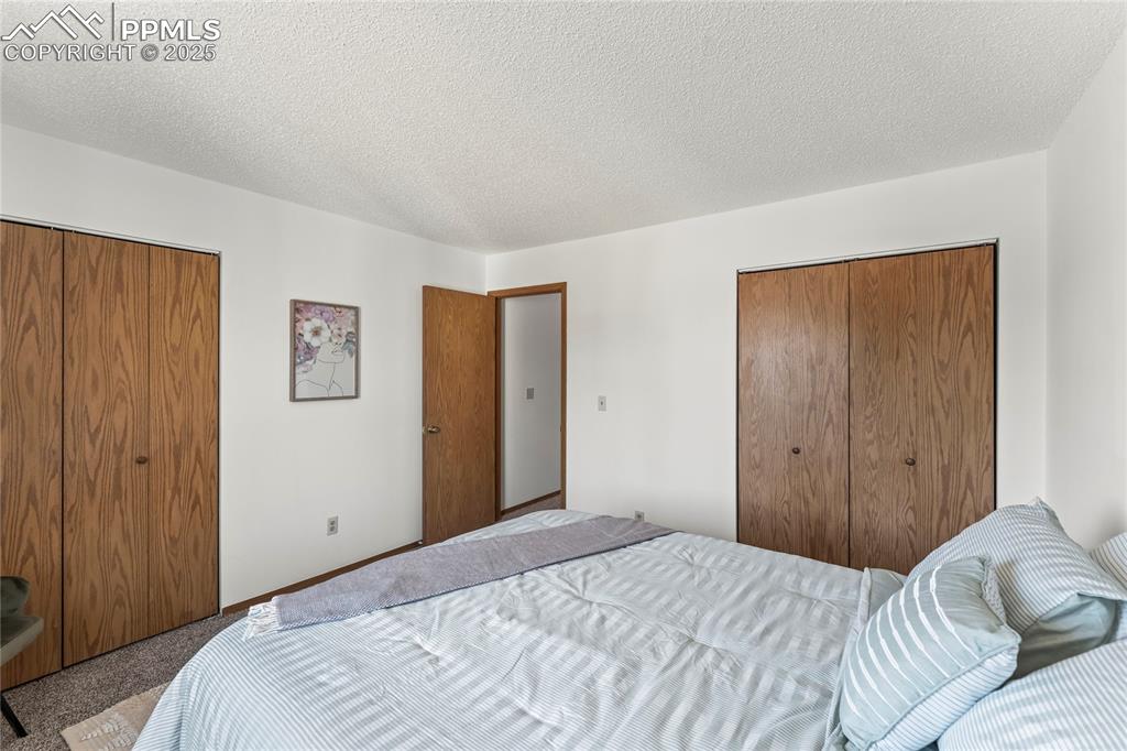 Image 20 of 25: Carpeted bedroom featuring two closets and a textured ceiling