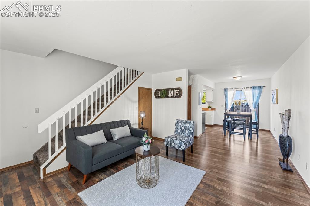 Image 4 of 25: Living area with stairway and dark wood-style flooring