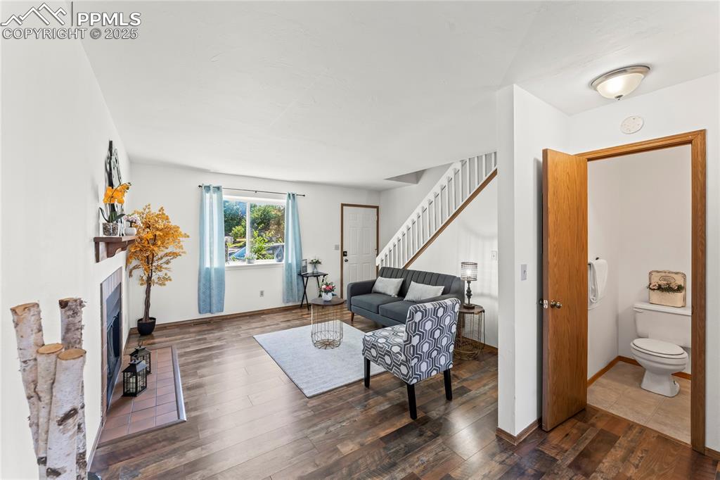 Image 5 of 25: Living area with dark wood finished floors, a fireplace, and stairs