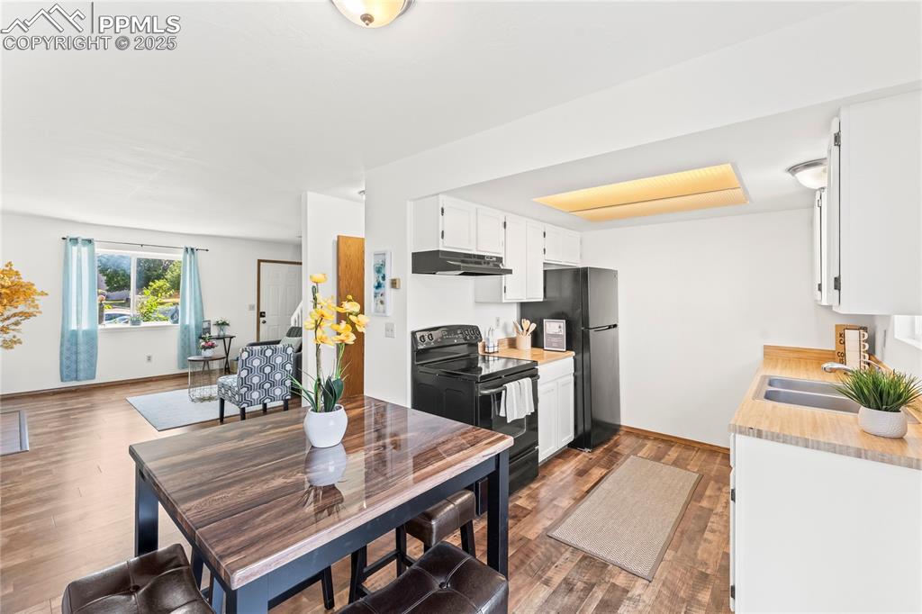 Image 9 of 25: Kitchen featuring white cabinets, light countertops, black appliances, dark