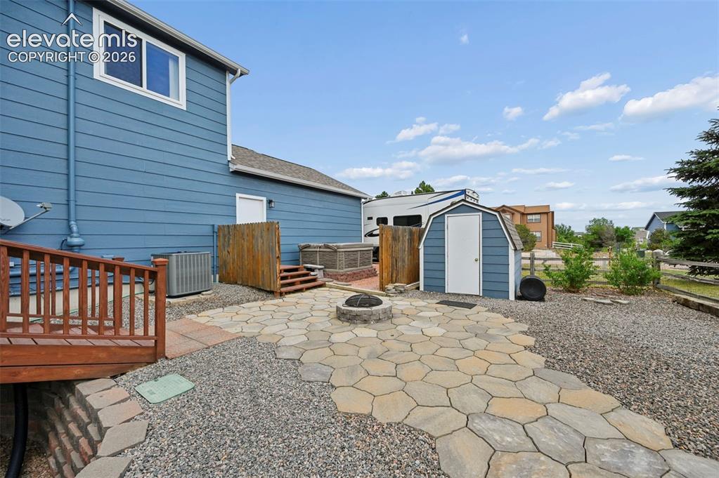 Image 48 of 49: Beautifully landscaped backyard area with firepit and storage shed