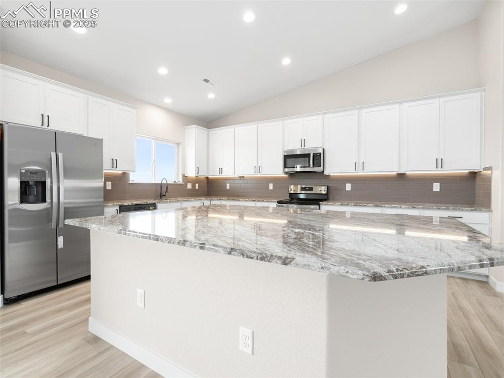 Image 11 of 38: Kitchen featuring white cabinetry, tasteful backsplash, stainless steel app