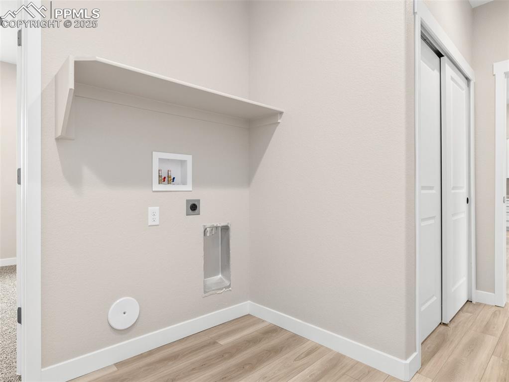 Image 15 of 38: Laundry room featuring light wood finished floors, washer hookup, and hooku