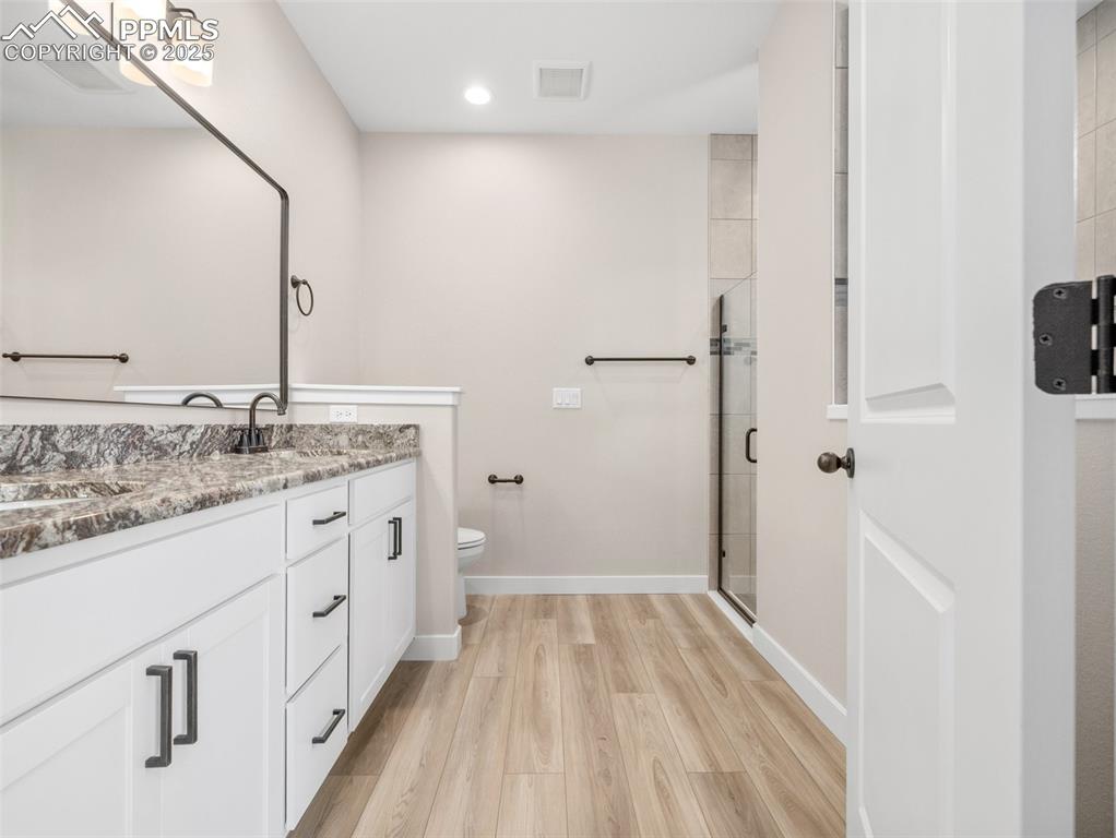 Image 27 of 38: Full bath with double vanity, a stall shower, light wood finished floors, a