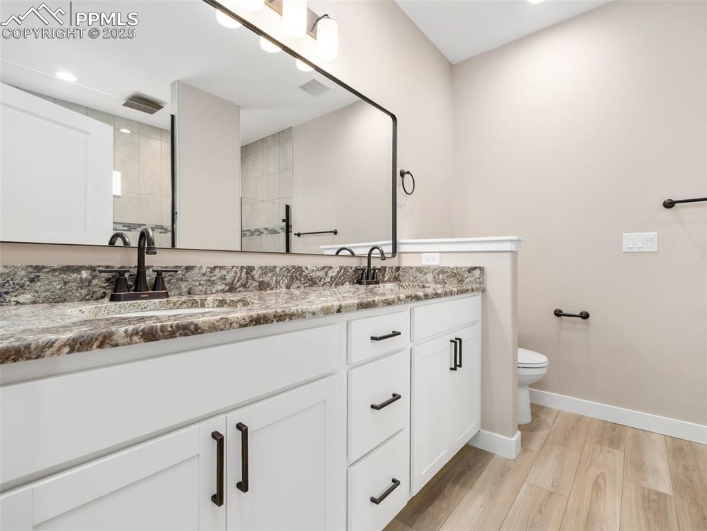Image 29 of 38: Bathroom featuring double vanity, light wood-type flooring, a walk in showe