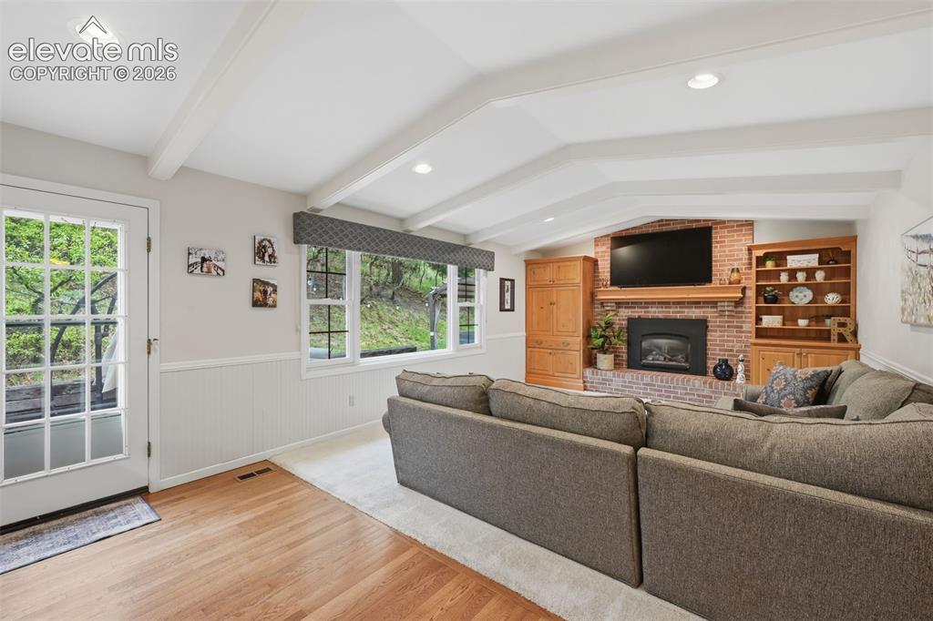 Image 19 of 49: Family room with fireplace off of kitchen with door to back patio