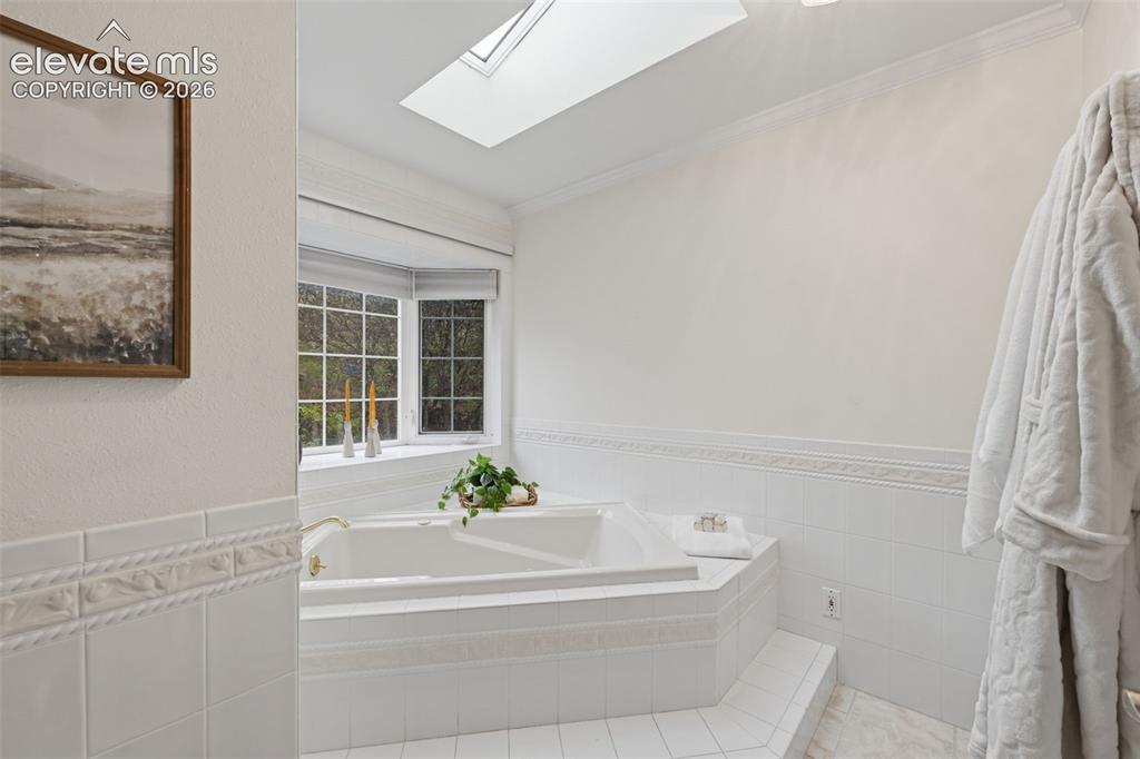 Image 27 of 49: Deep soaker tub in primary bath with separate shower