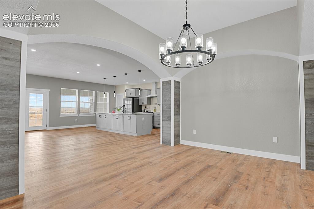 Image 11 of 49: Open-concept living area featuring wood-finish flooring, arched doorways, a