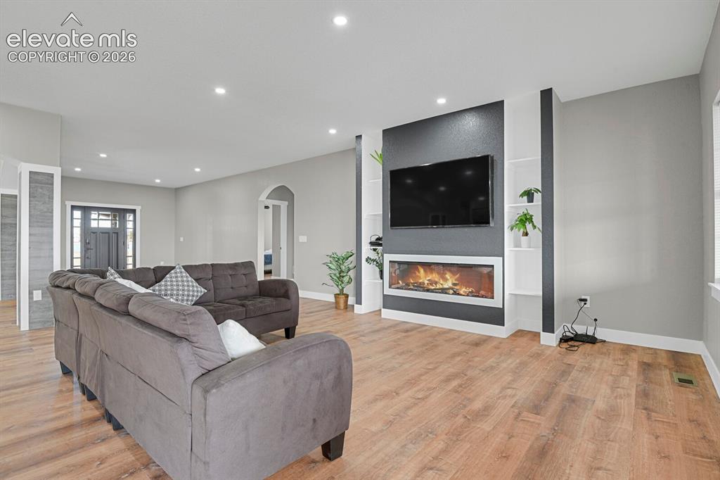 Image 14 of 49: Recessed lighting illuminates the wood-finish flooring and a built-in media