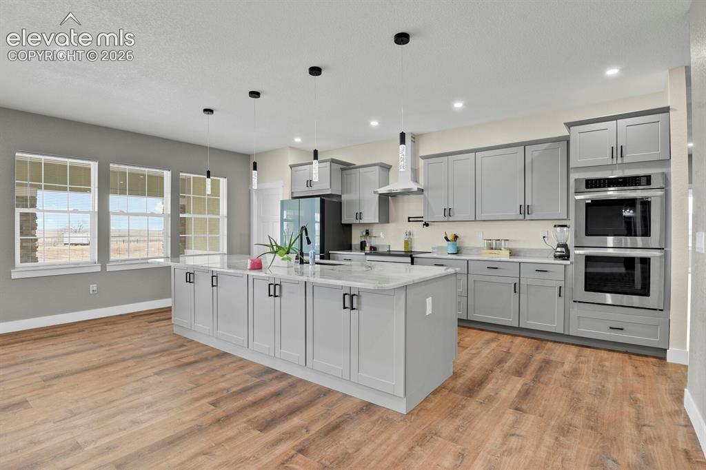 Image 17 of 49: Kitchen featuring gray shaker-style cabinetry, a large center island with a