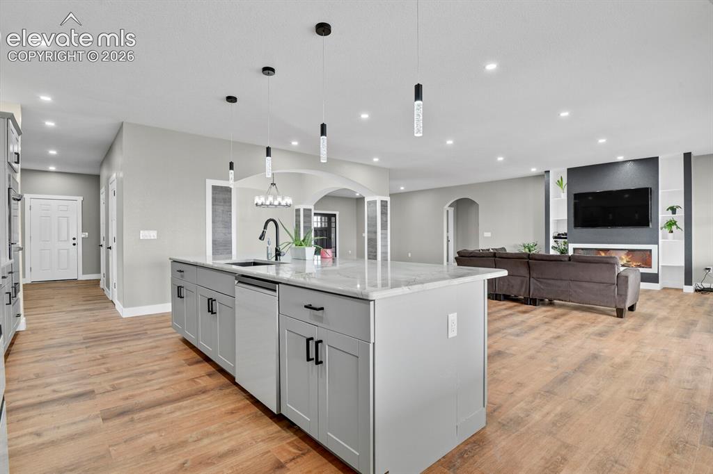 Image 19 of 49: Kitchen island with stone countertop, wood-finish flooring, recessed lighti